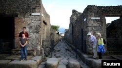 FILE - Tourists look down an ancient Roman cobbled street at the UNESCO World Heritage site of Pompeii, Italy.