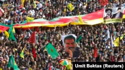 People wave Kurdish flags and hold up a picture of jailed Kurdish militant leader Abdullah Ocalan (C) of the Kurdistan Workers Party (PKK) during a gathering celebrating Newroz, which marks the arrival of spring and the new year, in Diyarbakir March 21, 2