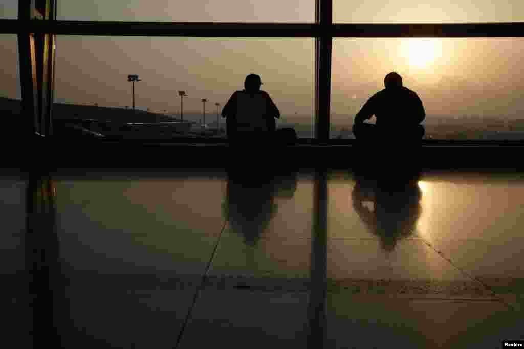 Men watch the runway on the morning of the final MH17 flight arriving at Kuala Lumpur International Airport. Malaysia Airlines retired flight number MH17 after its Amsterdam to Kuala Lumpur flight was shot down over the Ukraine.