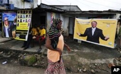 Une femme passant devant une affiche d'Alpha Condé à Conakry