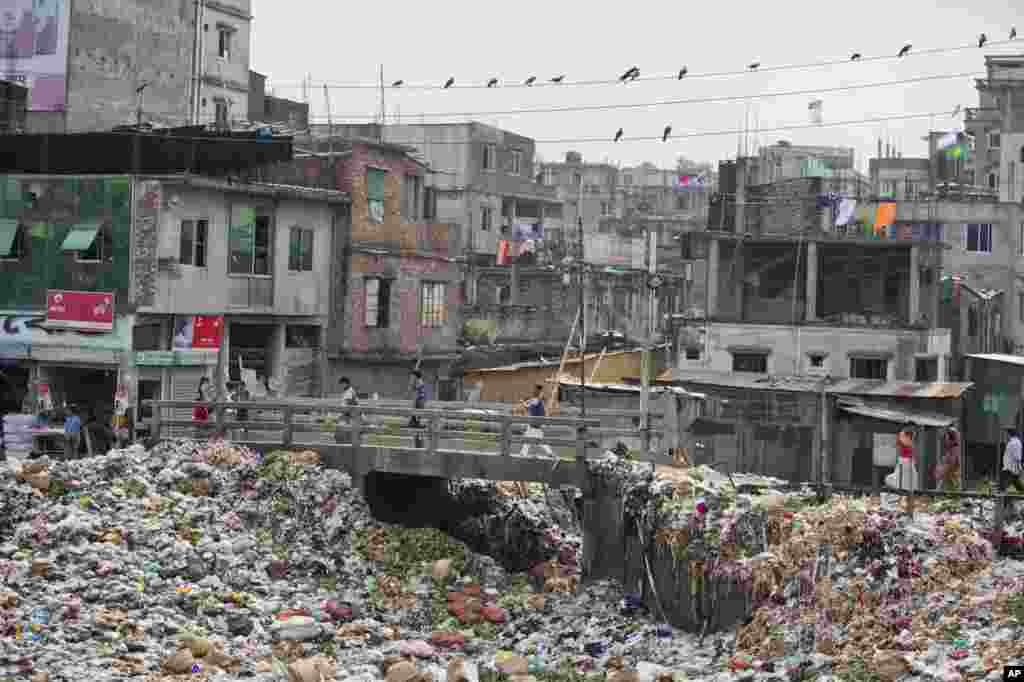 People walk across a bridge on the river Buriganga, choked with plastic and other waste, in Dhaka, Bangladesh.