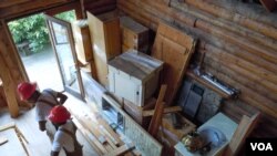 Workers from Second Chance remove all usable material from a log cabin which is scheduled to be torn down. (J. Taboh/VOA)