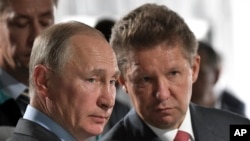 FILE - Russian President Vladimir Putin, left, and Alexei Miller, Russian natural gas giant Gazprom CEO, attend a meeting in Novobureyskiy, Russia, on Aug. 3, 2017. 