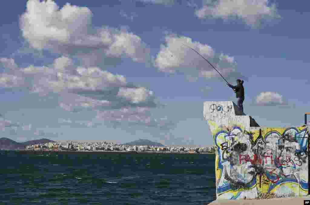A man fishes at Alimos seaside district of Athens, Greece.
