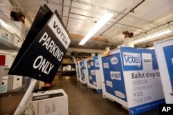FILE - Ballot drop boxes are stored with other voting equipment in a warehouse portion of the King County elections office in Renton, Wash., Sept. 19, 2018.