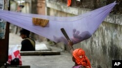 FILE - A woman laborer pacifies her child while cleaning a manhole on a sidewalk in Mumbai, India. Approved in September 2015, the sweeping 15-year agenda approved by the 193 U.N. member states is a global "to-do" list to tackle such issues as climate change, education, hunger, joblessness and land degradation.