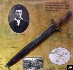 FILE - A photo of abolitionist John Brown is seen at the John Brown Museum in Osawatomie, Kansas, May 17, 2000, with a broadsword similar to ones used by Brown and his sons.