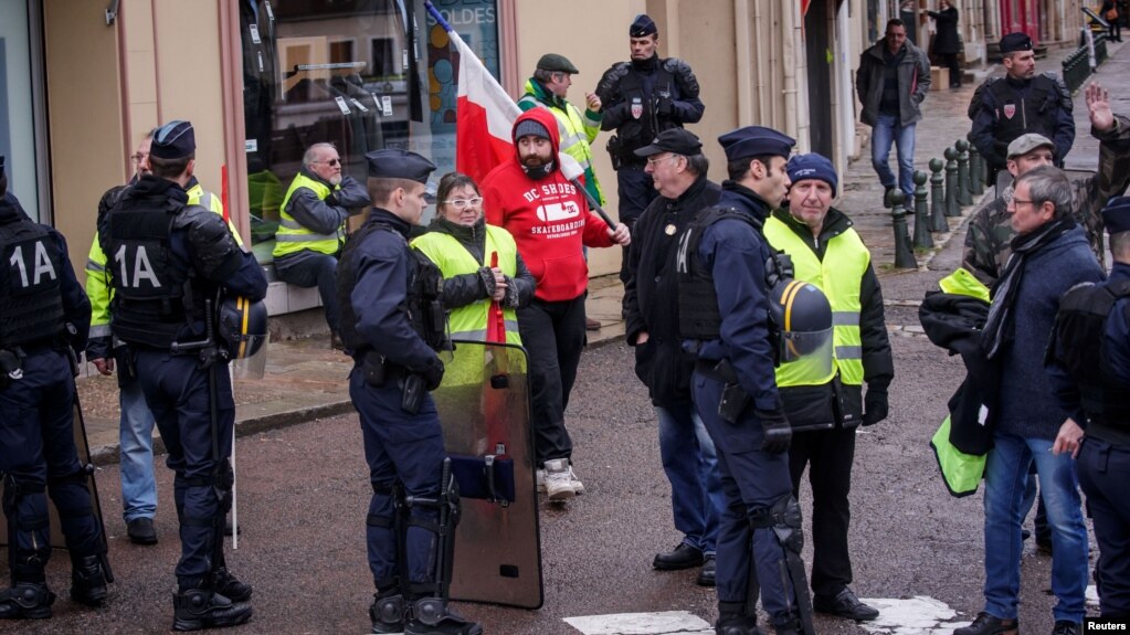 Protesters of the 'Gilets Jaunes' (Yellow Vests) movement await French President Emmanuel Macron's arrival, during his meeting with the mayors of the Saone-et-Loire department, in Autun, France Feb. 7, 2019.
