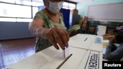 Une électrice dépose son bulletin de vote dans l'urne lors du 1er tour de l'élection présidentielle à Santiago, au Chili, le 21 novembre 2021. 