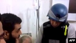 An image grab taken from a video posted by Syrian activists on Aug. 26, 2013 allegdly shows a UN inspector (R) listening to the testimony of a man in the Damascus subburb of Moadamiyet al-Sham.