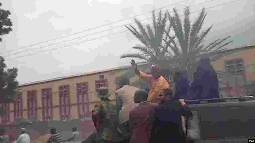 Manjo Hamza Al-Mustapha waves to people escortin ghim as he arrives in Kano.