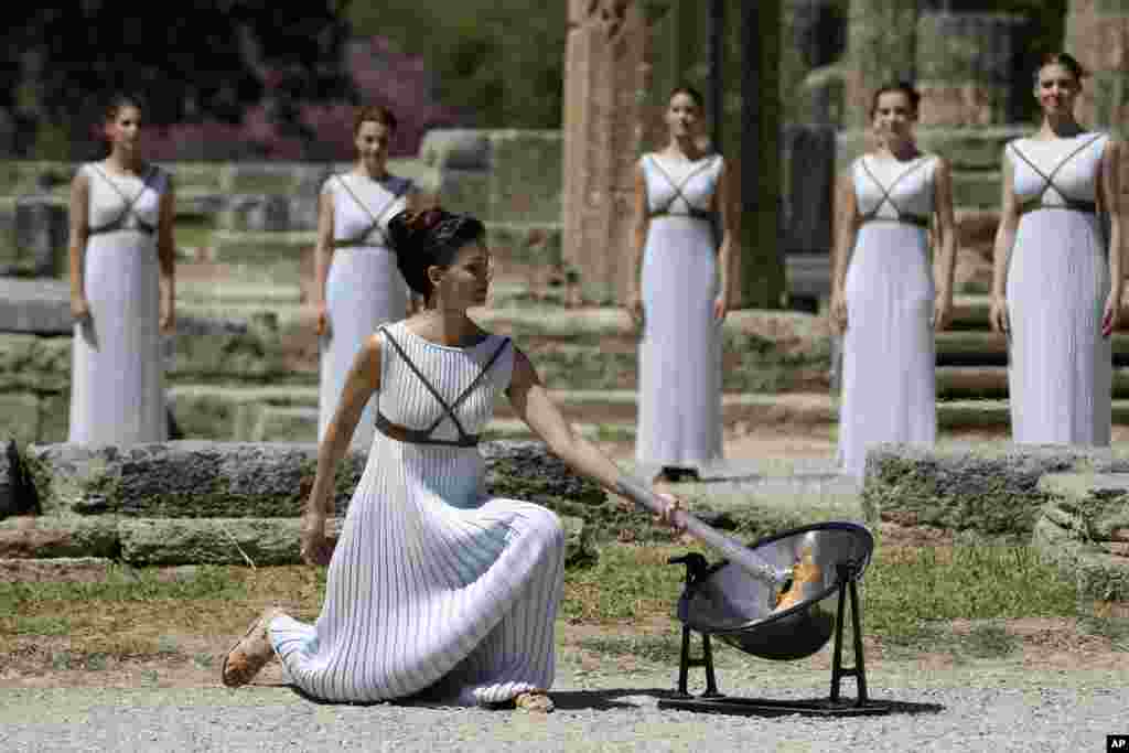 Actress Katerina Lehou, right, as high priestess, lights the Olympic Flame, during the final dress rehearsal of the lighting of the Olympic flame at Ancient Olympia, in western Greece. The flame will be transported by torch relay to the Brazilian city of Rio de Janeiro, which will host the Aug. 5-21, 2016 Olympics.
