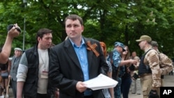 Secessionist referendum official Alexander Malyhin holds a document as he speaks to journalists in the eastern Ukrainian city of Luhansk May 12, 2014.