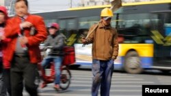 A worker crossing a street in Beijing, March 22, 2013.