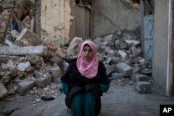 Amna Mahmoud Alo sits outside her house in a neighborhood recently retaken by Iraqi security forces from Islamic State militants, in west Mosul, Iraq, April 5, 2017.