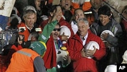 Miner Luis Urzua, the last miner to be rescued, center wearing green, celebrates next to Chile's President Sebastian Pinera after being rescued from a collapsed gold and copper mine, 13 Oct 2010