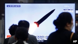 2021年3月25日，在韩国首尔的一个火车站，人们正在观看播放朝鲜发射弹道导弹的电视新闻节目。（美联社）