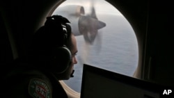 FILE - A flight officer aboard a Royal Australian Air Force plane searches for signs of missing Malaysia Airlines Flight MH370 in the southern Indian Ocean off Australia, March 22, 2014.