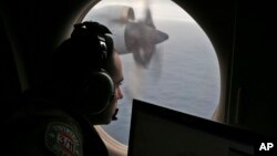 FILE - In this March 22, 2014, photo, a flight officer aboard a Royal Australian Air Force plane, searches for signs of missing Malaysia Airlines Flight MH370 in the southern Indian Ocean off Australia.