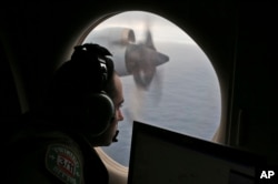 FILE - In this March 22, 2014, photo, a flight officer aboard a Royal Australian Air Force plane, searches for signs of missing Malaysia Airlines Flight MH370 in the southern Indian Ocean off Australia.