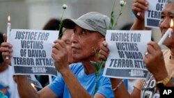 FILE - Protesters display placards during a prayer vigil in Manila, Philippines, for the victims of an explosion in Davao City, Philippines, Sept. 3, 2016. Suspected Abu Sayyaf extremists detonated a bomb at the night market in Davao City, killing a number of people and injuring dozens.