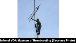 Mike Murphy of KA8ABR in Dayton adjusts the top of a radio antenna on the campus of the National VOA Museum of Broadcasting