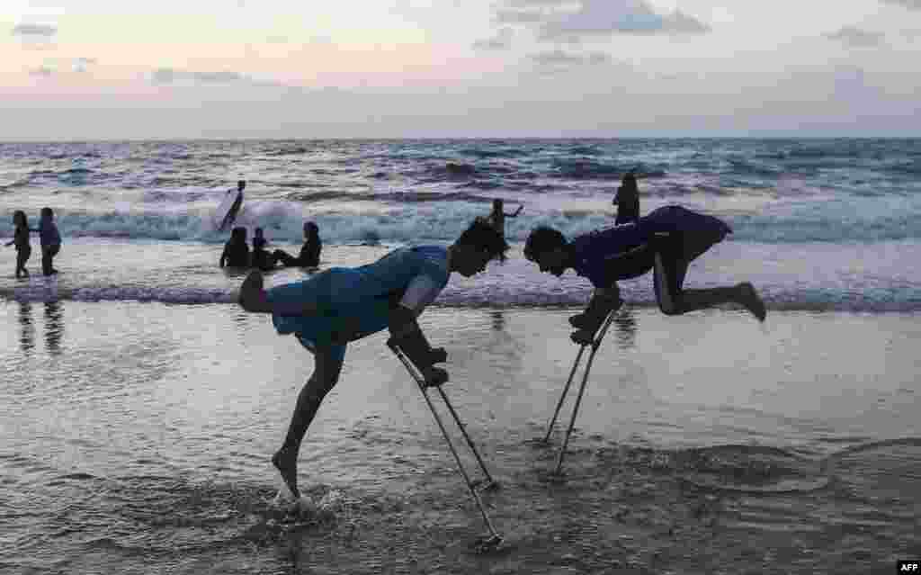 Palestinians Mohammed Eliwa, 17, and Ahmed al-Khoudari (R), 20, both of whom lost their legs during clashes on the border with Israel, play on the beach in Gaza City, Aug. 20, 2019.