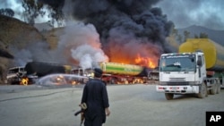 A security official stands near oil tankers - carrying fuel to US-led NATO forces in the northwestern tribal region of Khyber - that were set ablaze by a bomb blast near the main border crossing of Torkham, on the outskirts of Landikotal in Afghanistan, J
