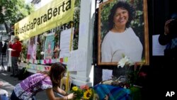 Seorang perempuan meletakkan bunga di altar yang dibuat untuk menghormati aktivis lingkungan hidup Berta Caceres dalam demonstrasi di luar Kedutaan Besar Honduras di Meksiko, 2016. (AP/Eduardo Verdugo)