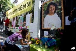 FILE - A woman places flowers on an altar set up in honor of Berta Caceres during a demonstration outside Honduras' embassy in Mexico City, June 15, 2016.