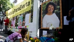 FILE - A woman places flowers on an altar set up in honor of Berta Caceres during a demonstration outside Honduras' embassy in Mexico City, June 15, 2016.