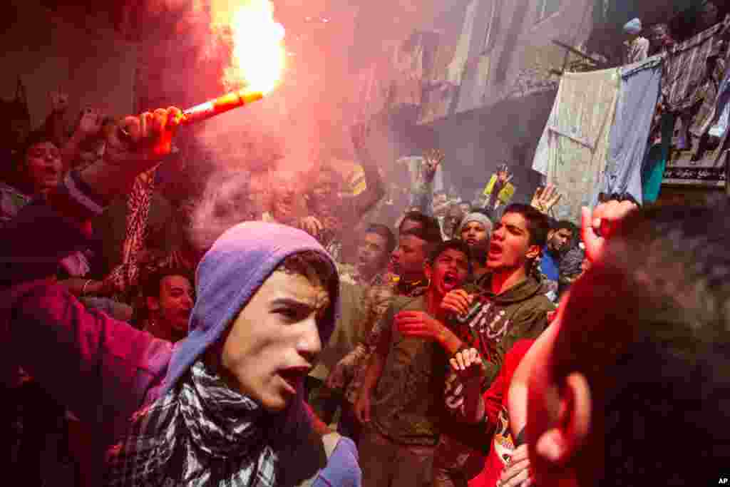 An Egyptian youth carries a lit flare as supporters of the Muslim Brotherhood gather in the El-Mataria neighborhood of Cairo, to protest the 20-year sentence for ousted president Mohammed Morsi and verdicts against other leaders of the Brotherhood.