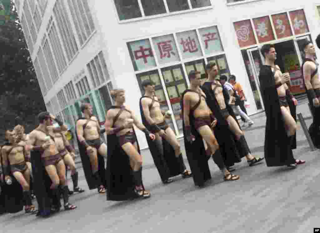Men dressed in Spartan-style costumes walk through a commercial plaza in Beijing, July 22, 2015. A salad store paraded dozens of half-naked Western men dressed as Spartans through China's capital as a publicity stunt, drawing a crackdown by police who were photographed restraining some of them on the ground.