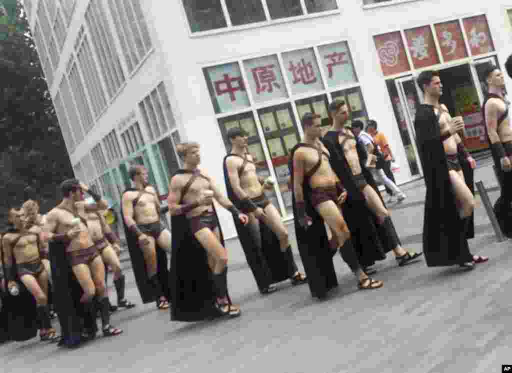 Men dressed in Spartan-style costumes walk through a commercial plaza in Beijing, July 22, 2015. A salad store paraded dozens of half-naked Western men dressed as Spartans through China&#39;s capital as a publicity stunt, causing a stir and drawing a crackdown by police who were photographed restraining some of them on the ground.