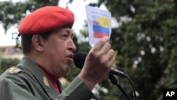Venezuela's President Hugo Chavez talks to supporters as he holds a picture of an old Venezuelan flag during a ceremony in Caracas July 14, 2011.