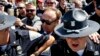 FILE - Alex Jones (C), an American conspiracy theorist and radio show host, is escorted out of a crowd of protesters after he said he was attacked in Public Square on July 19, 2016, in Cleveland, Ohio.