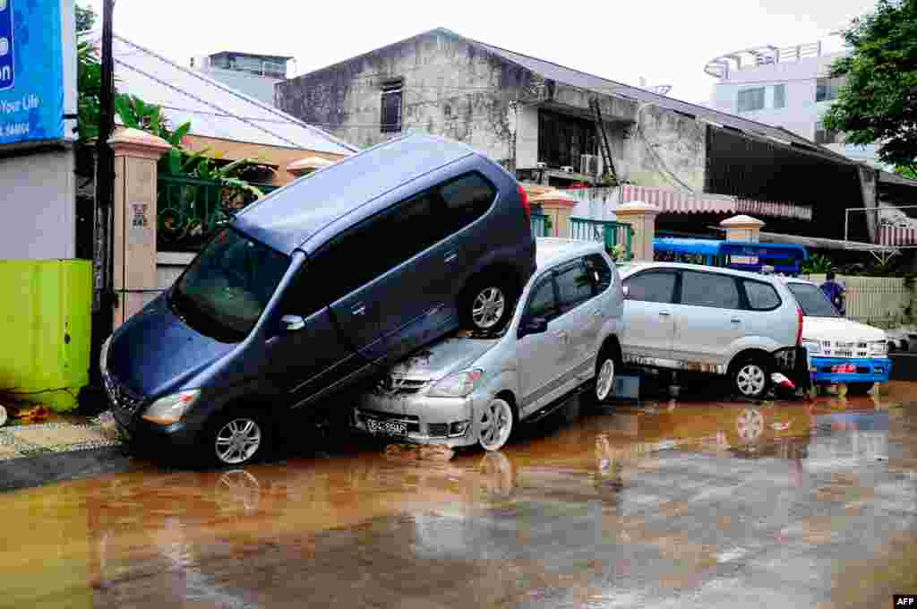 Cars are seen on top of each other after being hit by flood waters in Manado. At least 13 people were killed after overnight flash floods and landslides hit Indonesia&#39;s Sulawesi island, an official said.