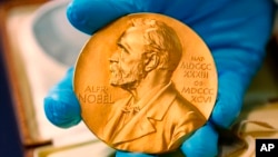 In this photo dated Friday, April 17, 2015, a national library employee shows the gold Nobel Prize medal awarded to the late novelist Gabriel Garcia Marquez, in Bogota, Colombia. The Swedish Academy said Friday that the 2018 prize for literature will be given in 2019.
