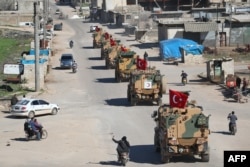 FILE - A column of armored Turkish military vehicles drives on a patrol along a road in the de-militarized zone in Syria's northern Idlib province near the town Saraqib, March 8, 2019.