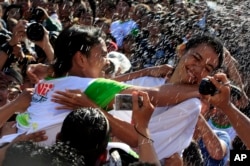 FILE - A Balinese girl, right, tries to avoid a kiss during the "Omed Omedan" kissing festival in Bali, Indonesia.
