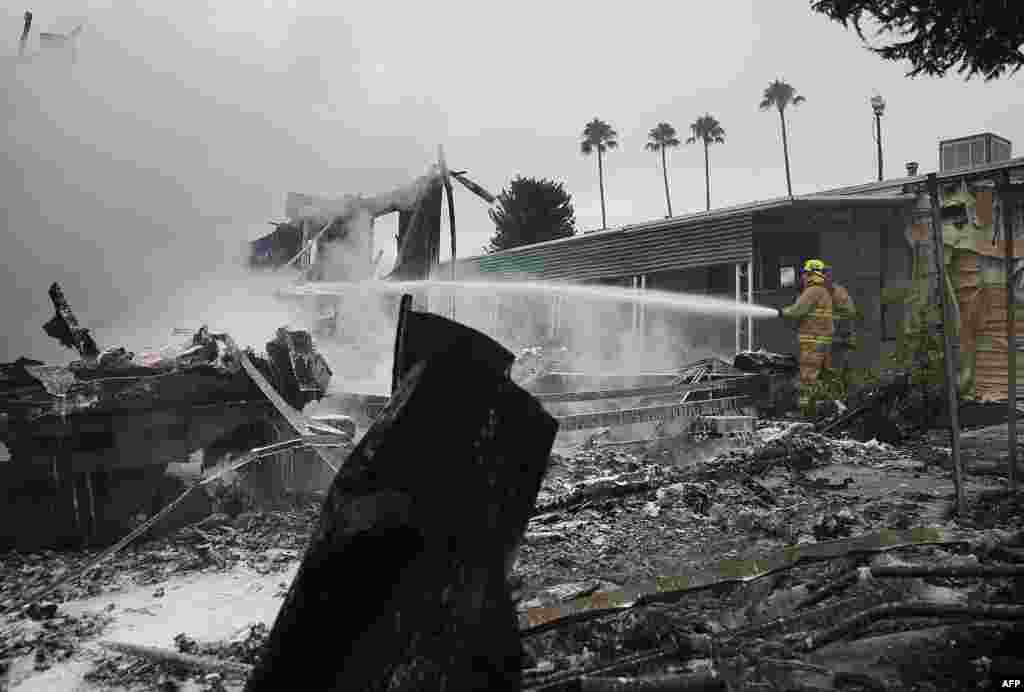 Napa County firefighters spray foam on hot spots from a fire at a mobile home park following a reported 6.0 earthquake in Napa, California.