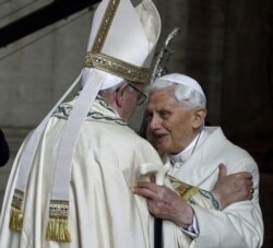 Paus Emeritus Benediktus XVI, kanan, memeluk Paus Francis di Basilika Santo Petrus selama upacara yang menandai dimulainya Tahun Suci, di Vatikan, Selasa, 8 Desember 2015. (Foto: AP)