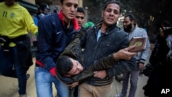 A protester wounded in clashes with security forces is evacuated from the site in the Mohandiseen district of Cairo, Egypt, Saturday, Jan. 25, 2014.