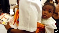 A mother carries a child on her back as she visits an exhibition on HIV/AIDS during the launch of UNICEF's "Unite for children, Unite against AIDS" global campaign in Gaborone, Botswana, Thursday, May 11, 2006. Nearly 37 percent of the adult population ha