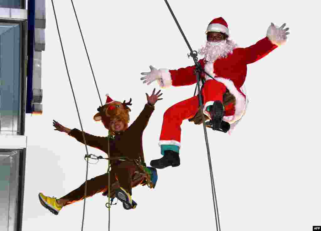 Workers in Santa Claus (R) and reindeer (L) costumes are pictured as they clean windows outside a shopping mall along Tokyo's waterfront, Japan.