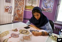 An Iranian woman sketches and paints carpet patterns at a workshop in the Cultural and Artistic Carpet Foundation of Rassam Arabzadeh in Tehran, Iran, Aug. 4, 2015.