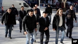 FILE - Four Turkish military officers in suits wearing handcuffs, center, escorted by Greek plainclothes police officers, arrive at the Supreme Court in Athens, Jan. 13, 2017.