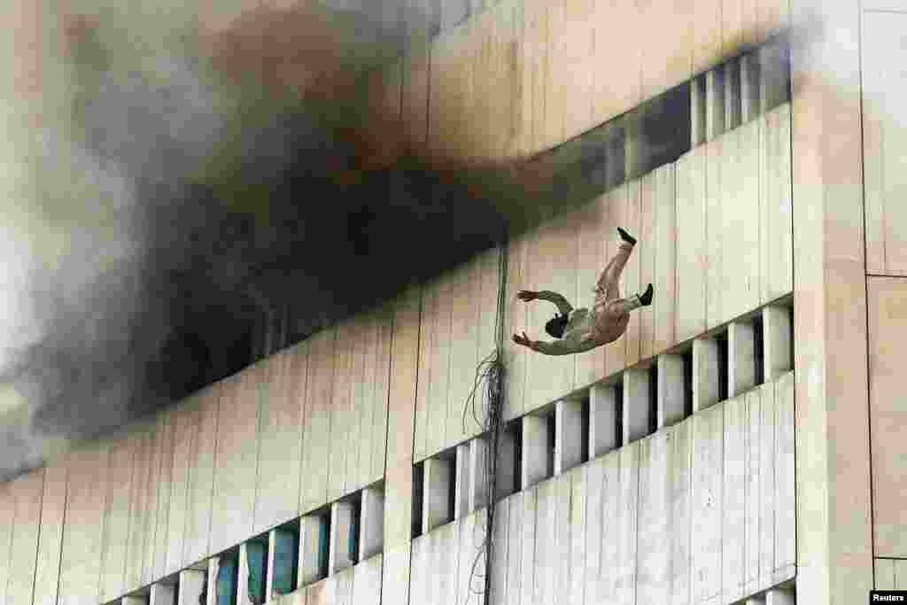 A man falls from a high floor of a burning building in central Lahore, Pakistan. Fire erupted on the seventh floor of the LDA plaza in Lahore and quickly spread to higher floors leaving many people trapped inside the building. 