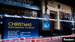 Seorang polisi tengah berjaga dekat papan pengumuman yang diberi garis polisi di luar Theater Apollo, London (20/12).
