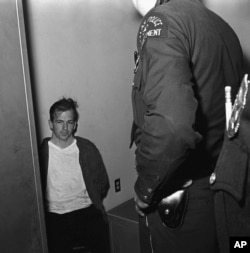 FILE - Lee Harvey Oswald sits in police custody shortly after being arrested in connection with the fatal shooting of President John F. Kennedy in Dallas, Texas, Nov. 22, 1963.